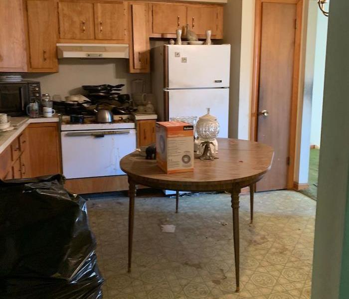 Kitchen with trash bags on the floor and pans on the stove
