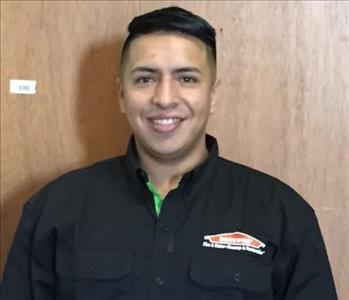 Male employee in a black logo SERVPRO jacket, posing