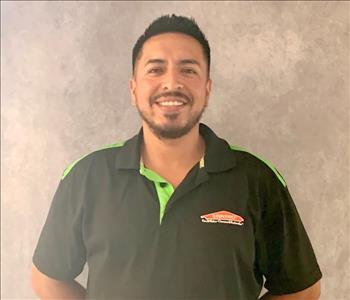 Male employee in a black logo SERVPRO jacket, posing