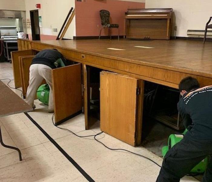 SERVPRO techs setting up air movers to dry underneath a church chancel