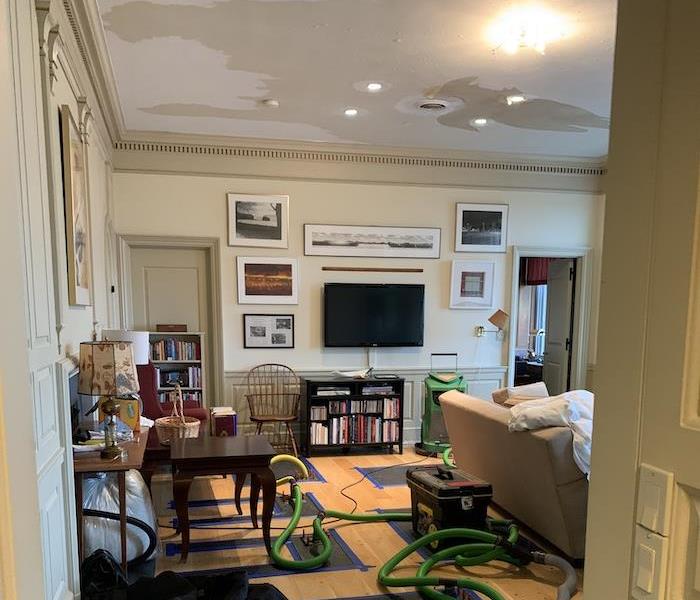 Living room with hardwood flooring being dried by drying mats